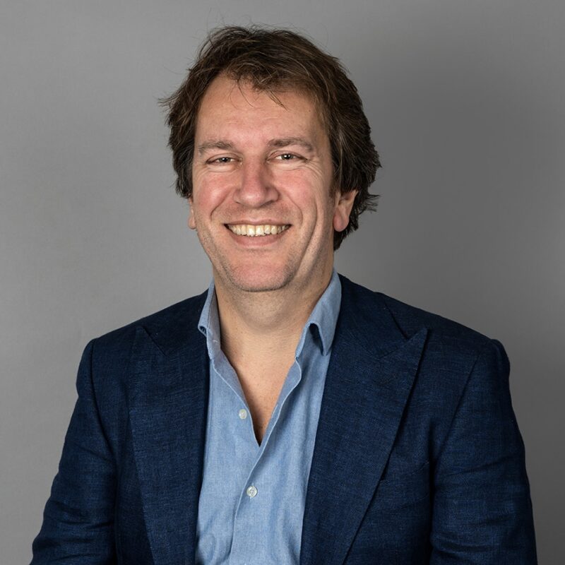 Smiling man in navy blazer and light blue shirt