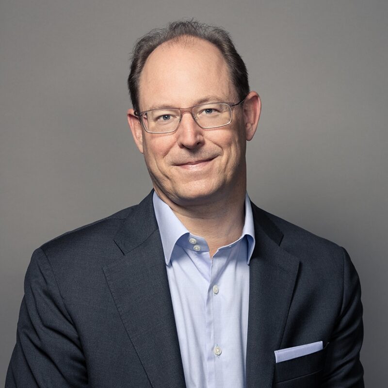 Professional man in dark blazer and glasses smiling confidently