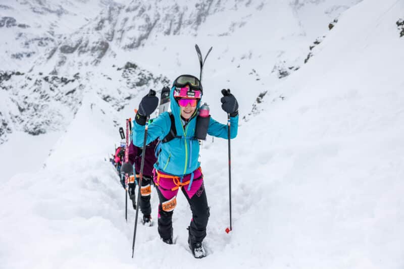 Ski mountaineering racers climbing snowy mountain slope with poles