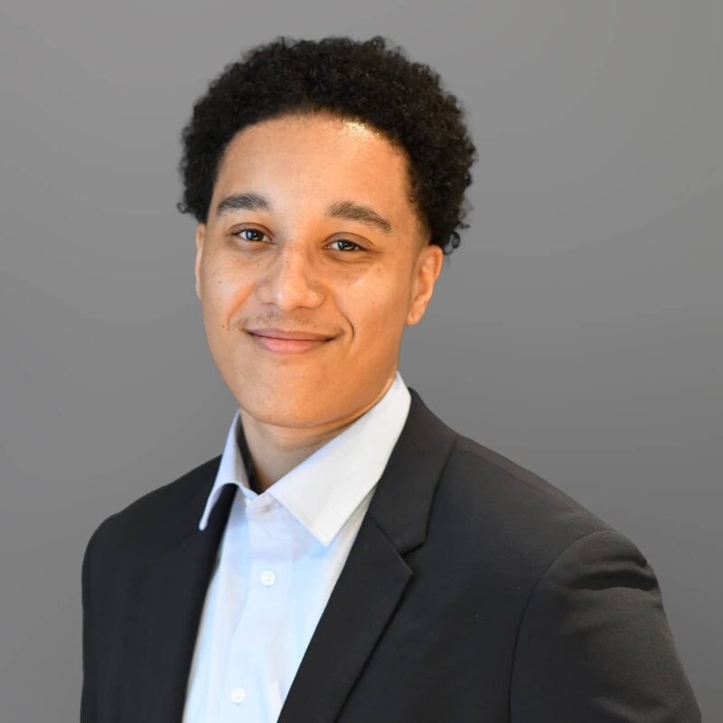 Young professional man smiling in black blazer and white shirt