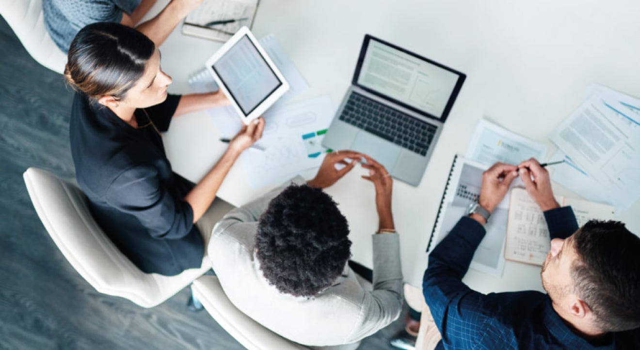 Overhead view of three professionals collaborating around office desk