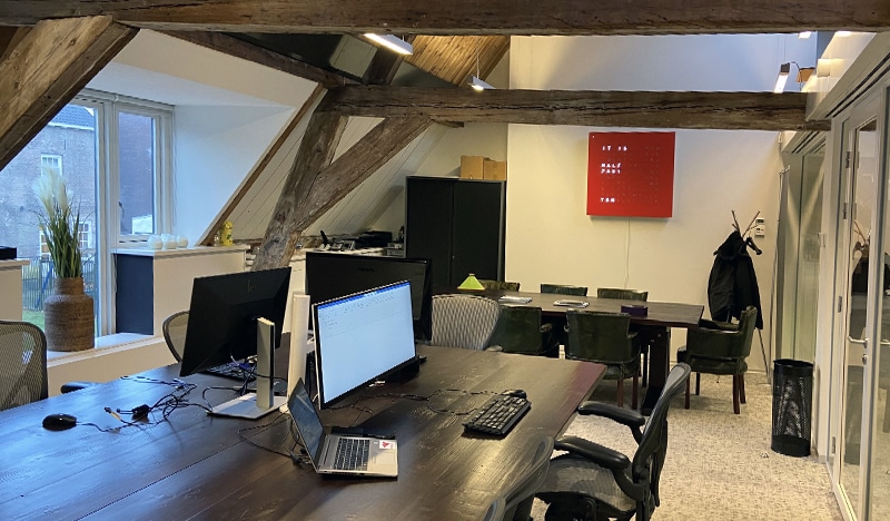 Modern office workspace with exposed wooden beams and computer monitors