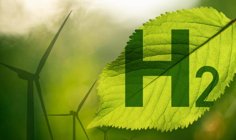 Green leaf with H2 symbol and wind turbines background