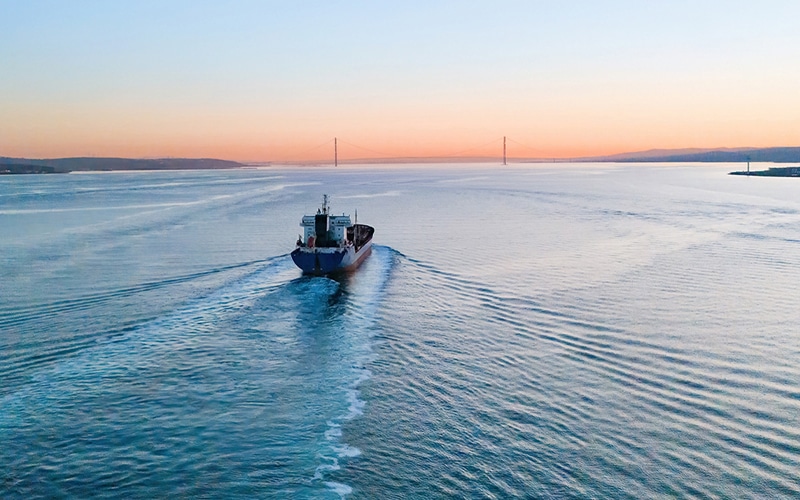 Cargo ship sailing on calm water at sunset
