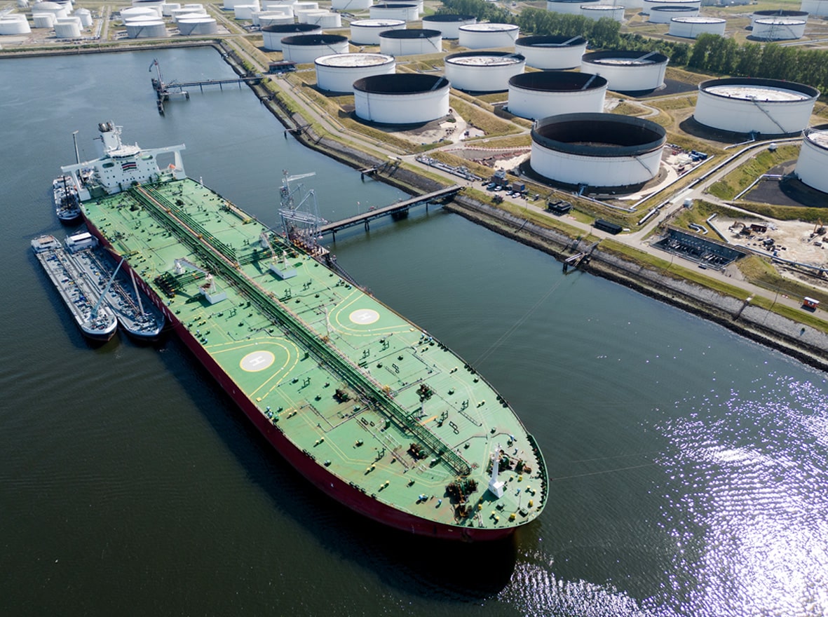 Aerial view of large oil tanker docked near storage tanks