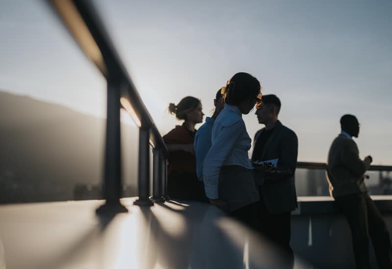 Group of professionals networking on rooftop at sunset